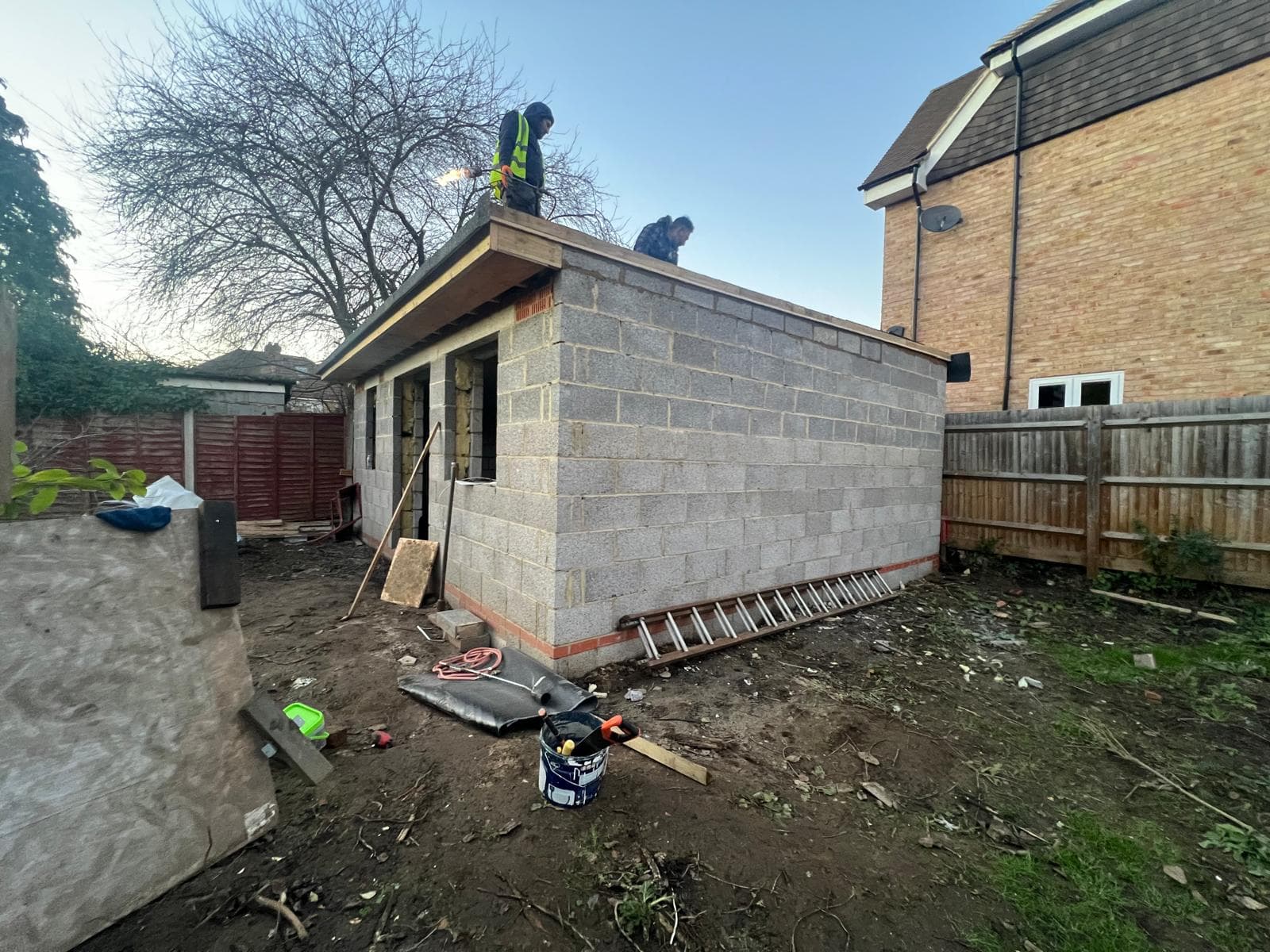 New outbuilding under construction in the garden, with the blockwork walls up and roof structure being completed