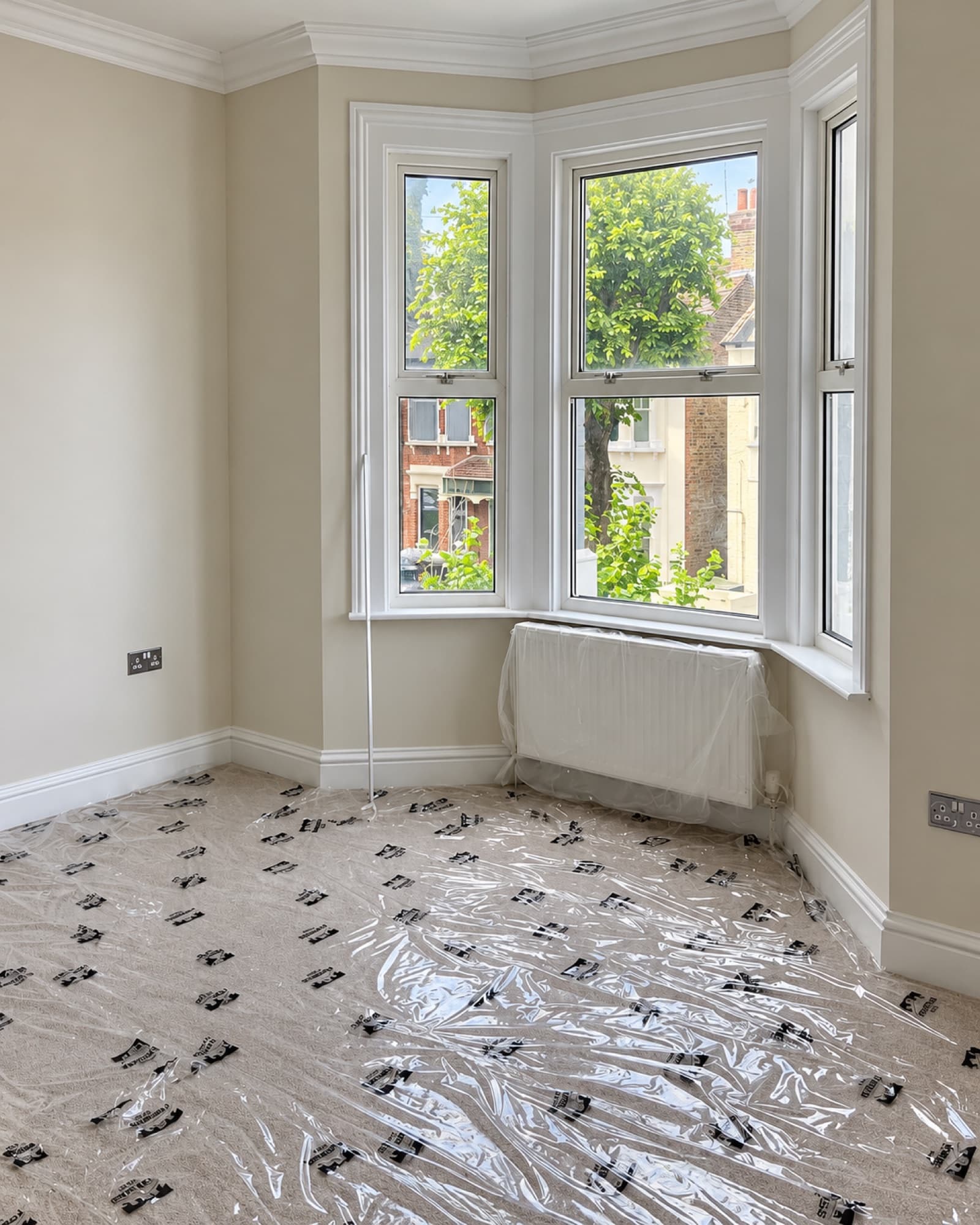 Freshly decorated bay window room with protective film still covering the carpet