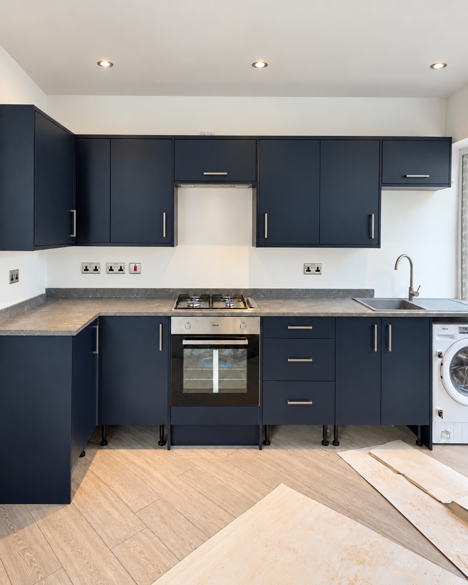 Navy blue fitted kitchen with integrated oven, gas hob and washing machine