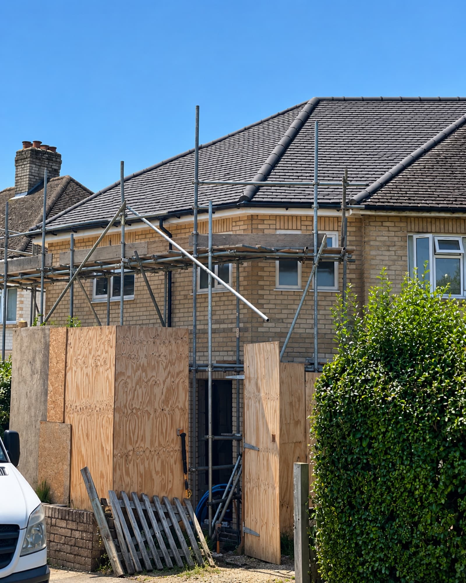 Side extension under construction, scaffolded with boarded-up openings
