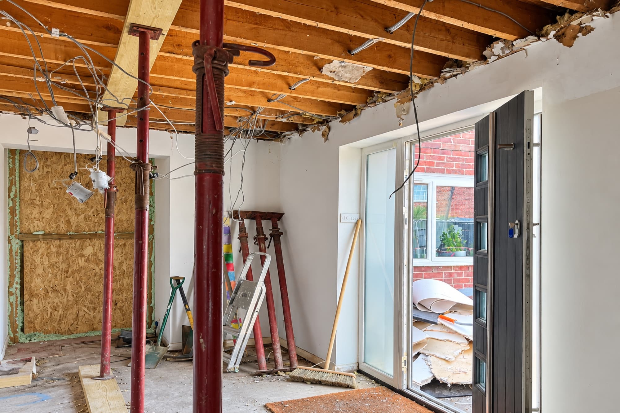 Acrow props supporting exposed ceiling joists during a structural renovation
