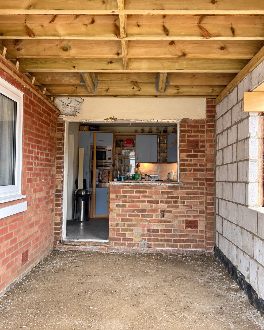 New-build extension roof structure opening into an existing kitchen