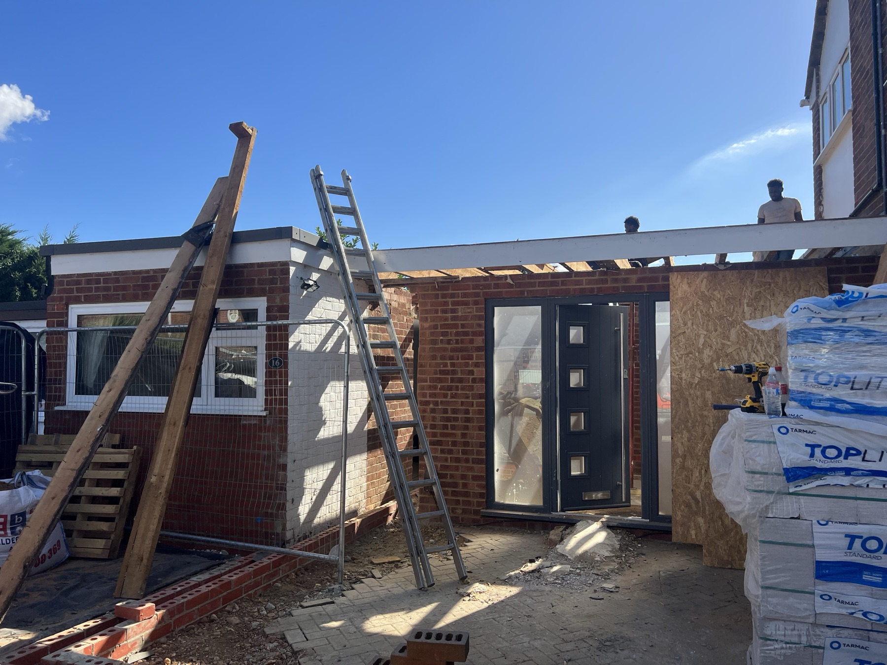 New front door and structural opening formed to the single storey portion of the side extension, with insulation boards and materials staged on site