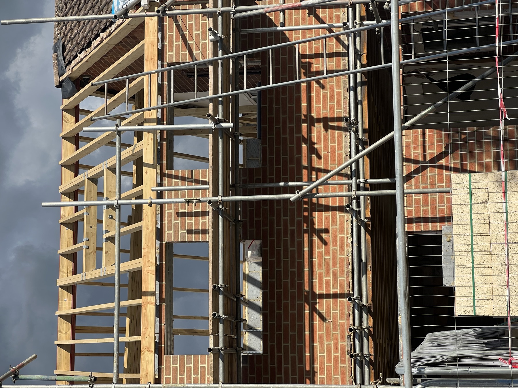 First floor brickwork going up around door and window openings, with scaffold boards in place