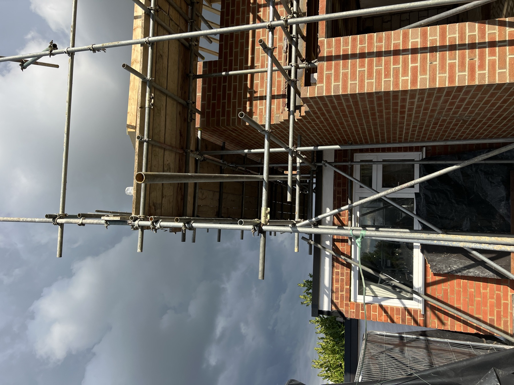 First floor brickwork with window openings formed, scaffolding still in place