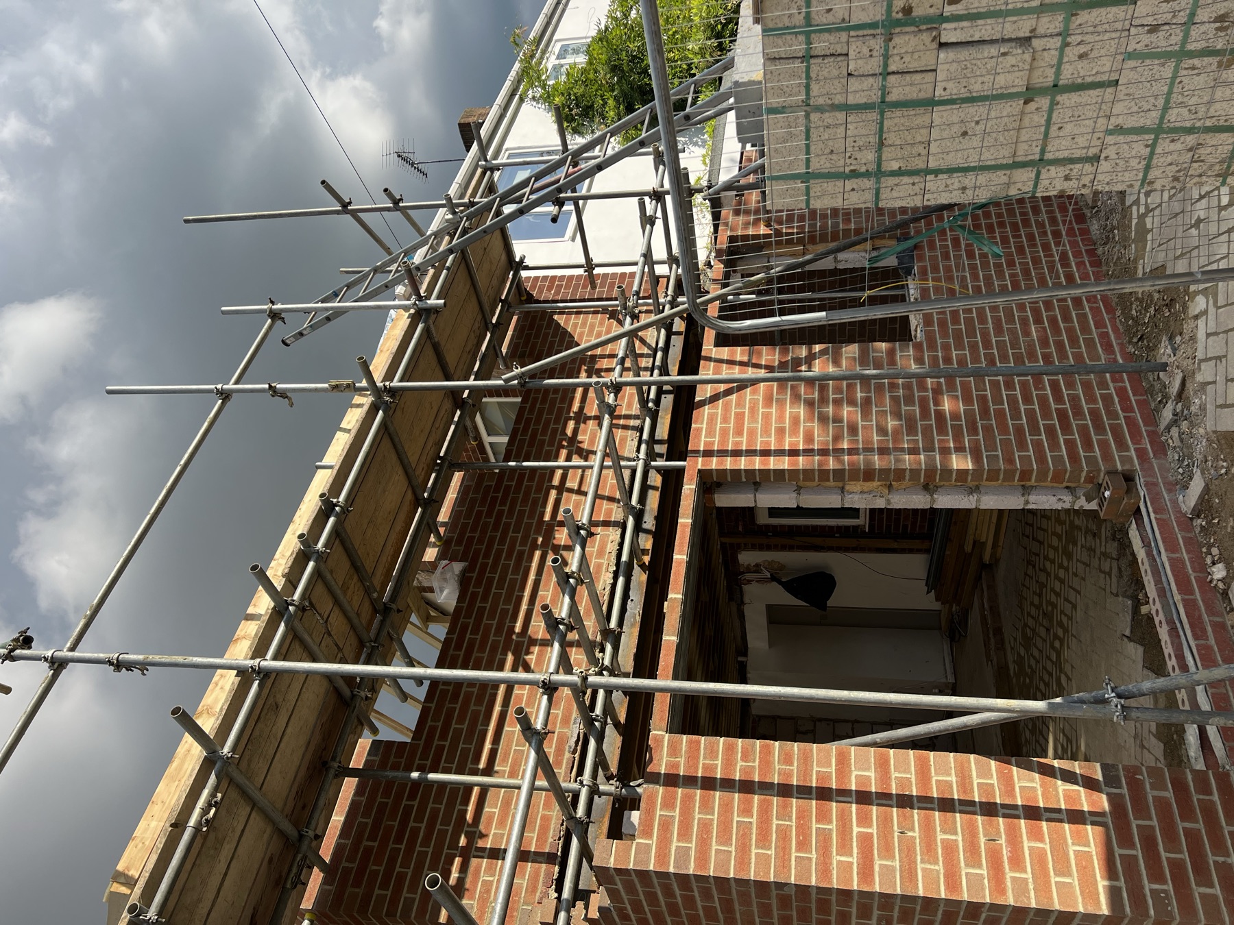First floor extension brickwork with a ground floor opening below, nearing completion