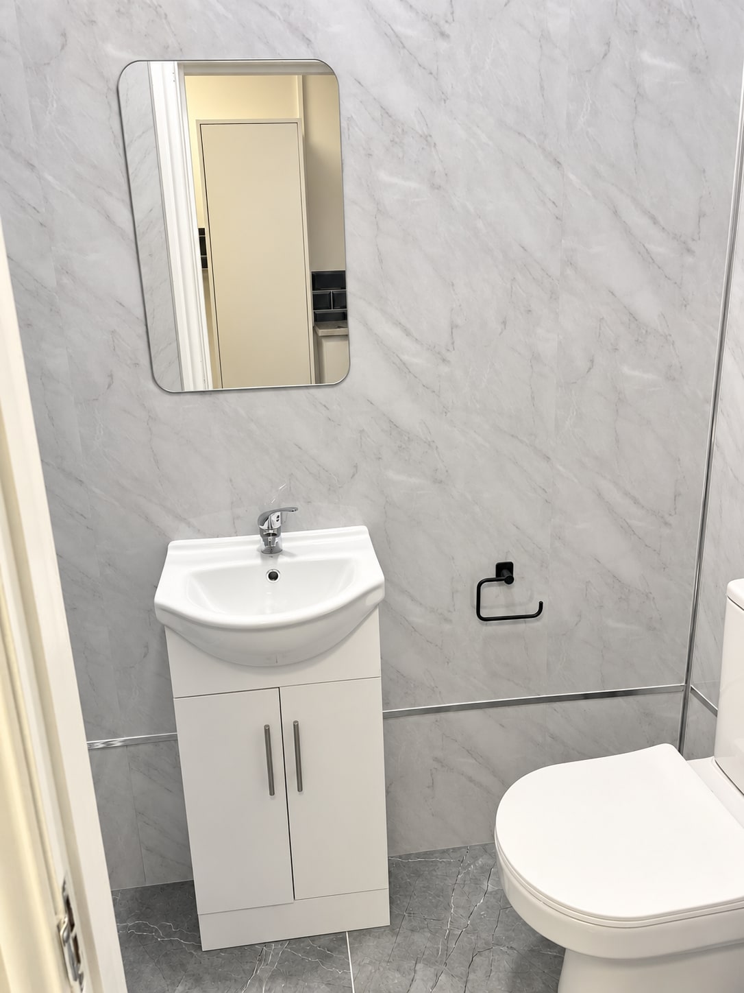 Bathroom with white vanity, mirror and marble-effect wall finish