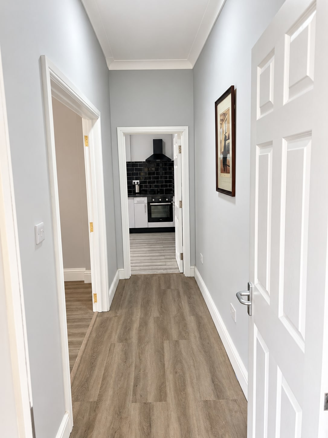 Refurbished hallway with grey walls, white joinery and wood-effect flooring