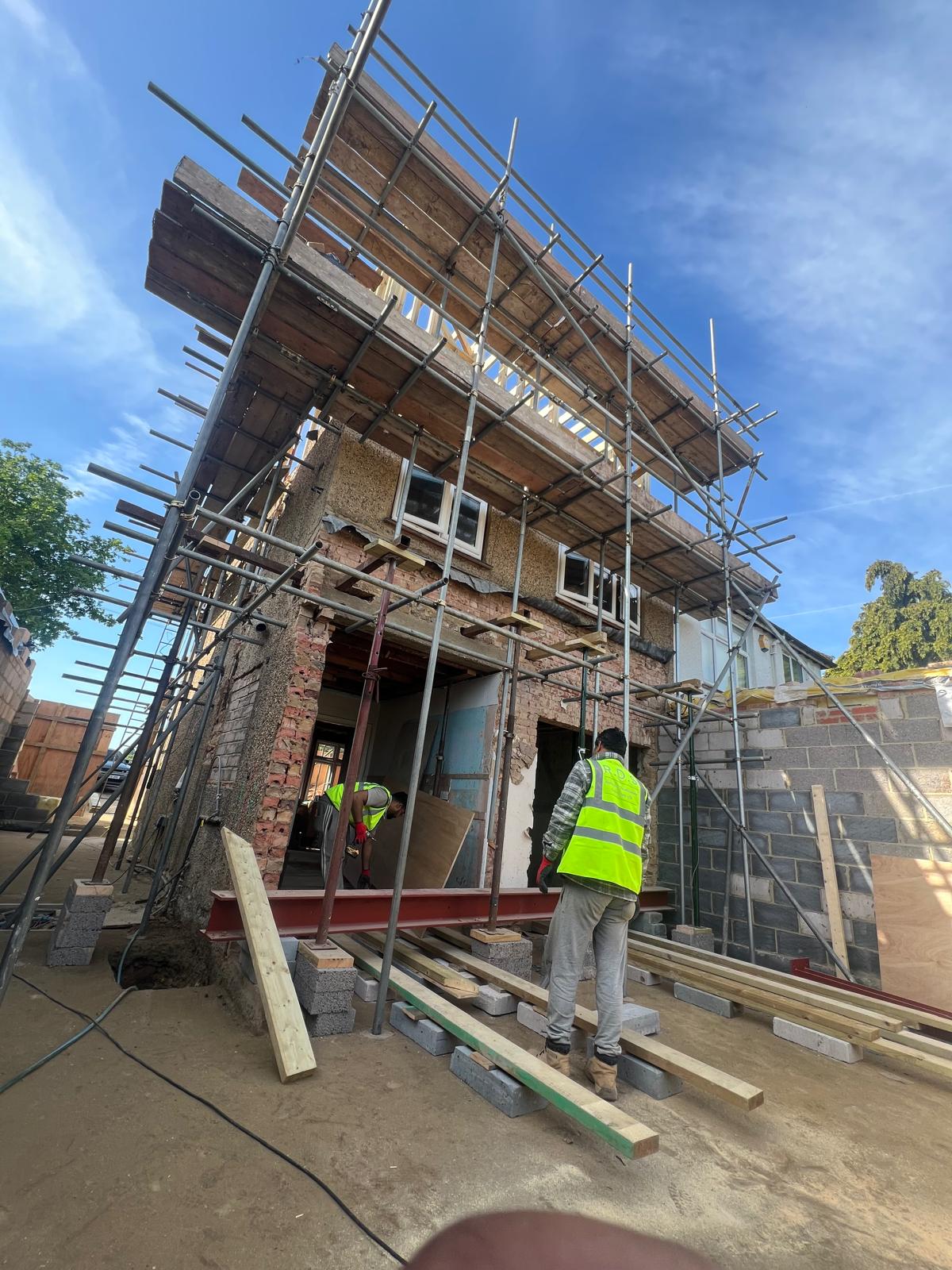 Structural steel beam being installed for the rear and side extension, with scaffolding to the existing house