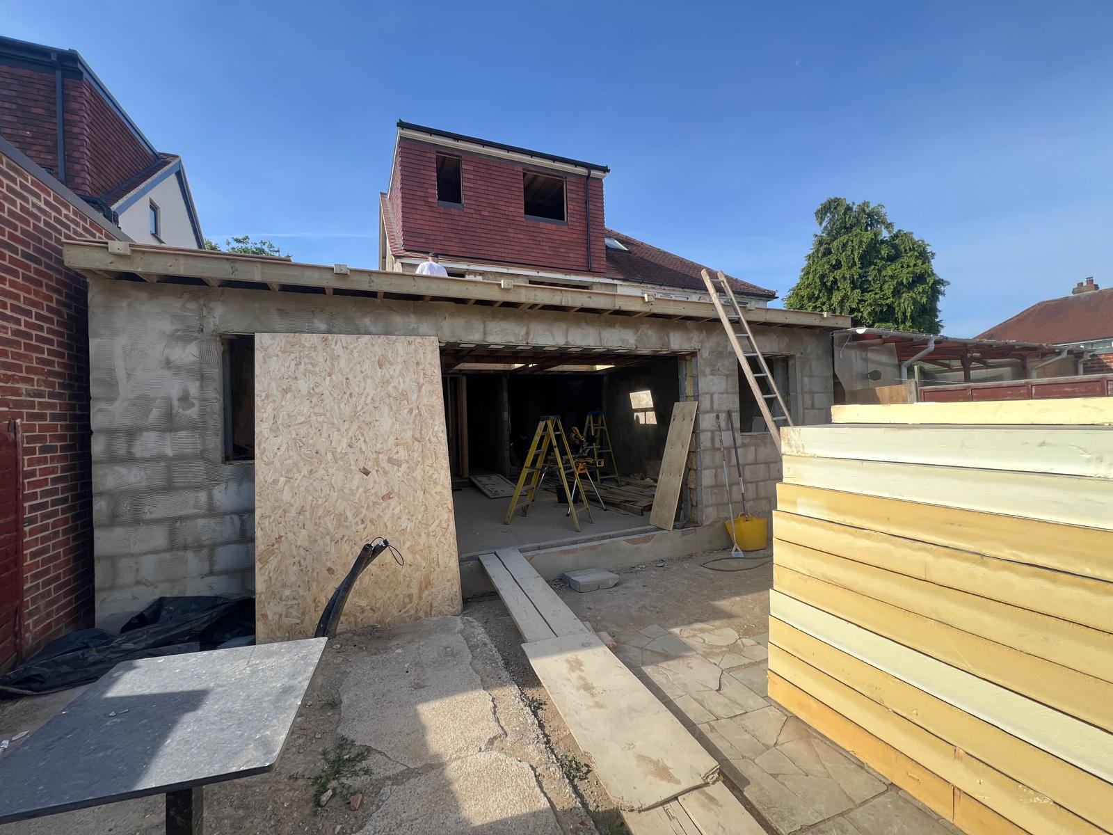 Extension roof structure and loft dormer under construction, with insulation boards stacked ready for fitting