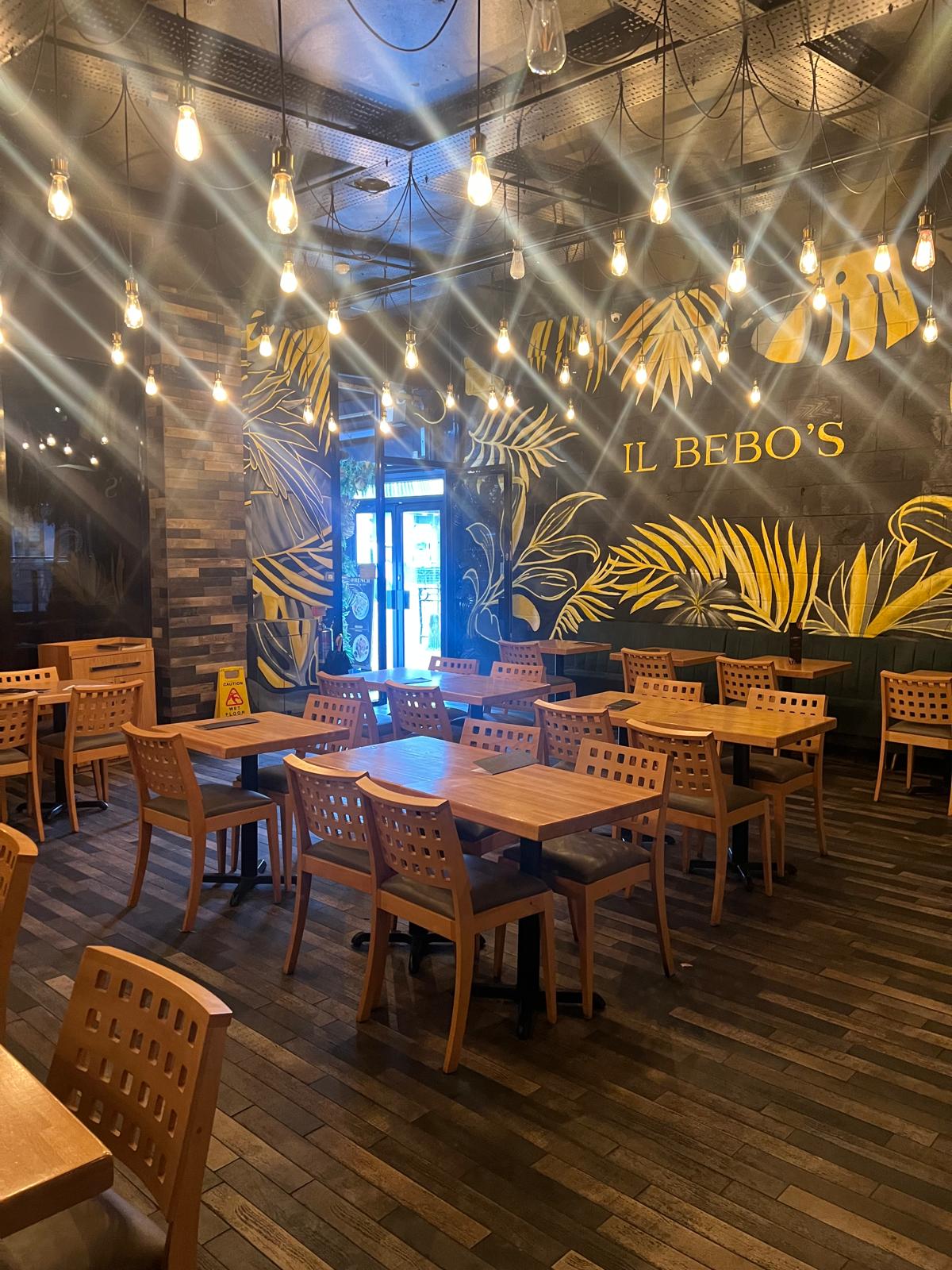 Interior of the existing restaurant before refurbishment, with a palm-leaf mural and pendant lighting
