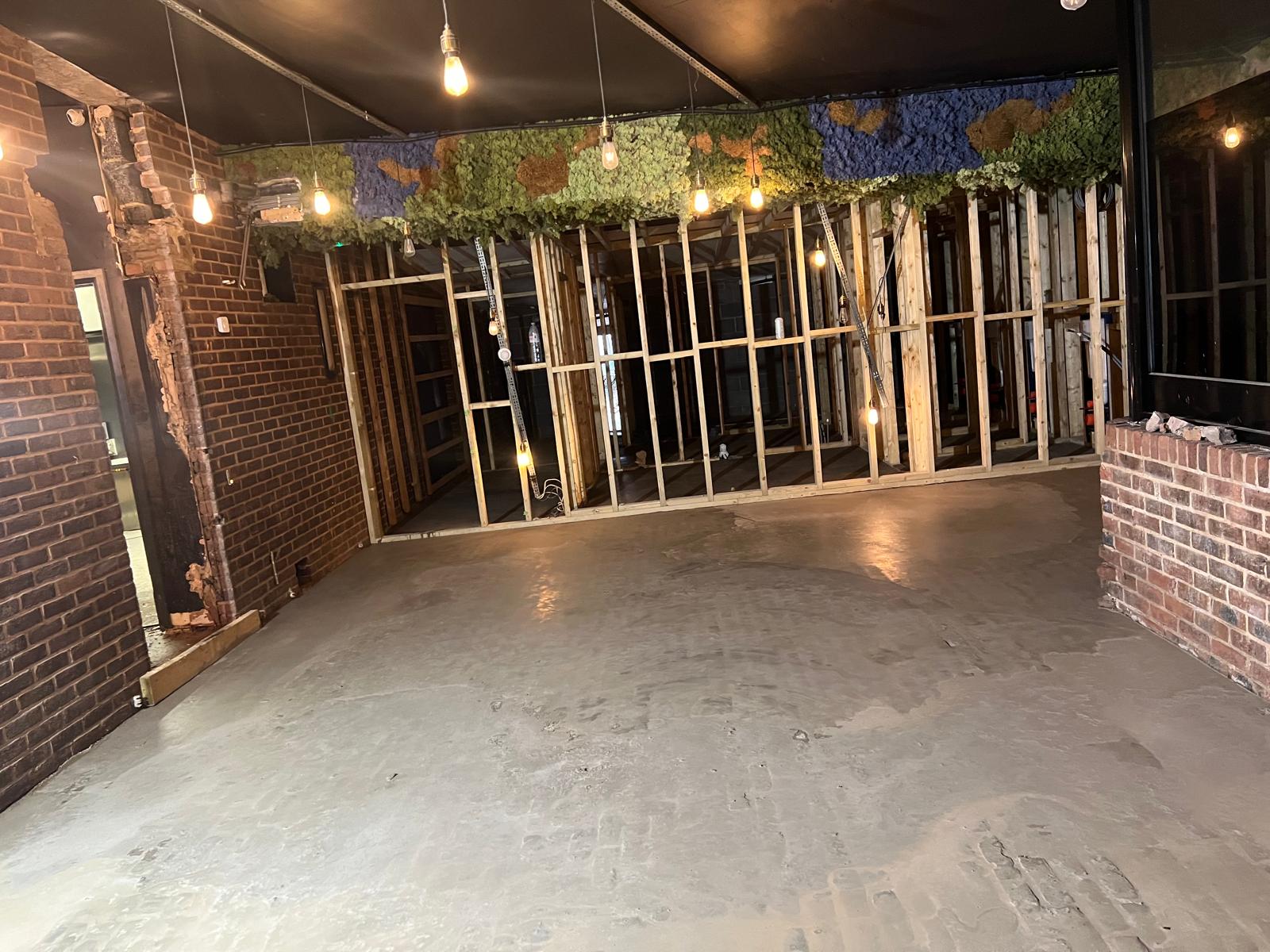 New stud wall framing and a freshly laid concrete floor during the rebuild