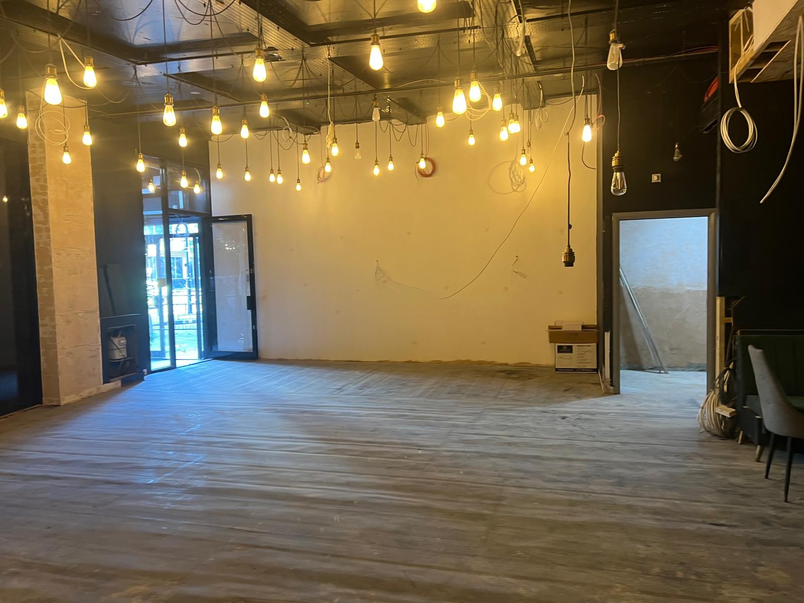 The main room during first fix, with pendant lighting hung and protective floor covering down