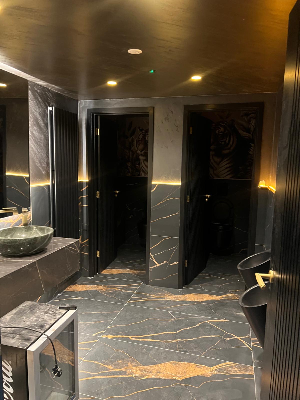 Completed washroom with a tiger mural, marble tiling and twin basins