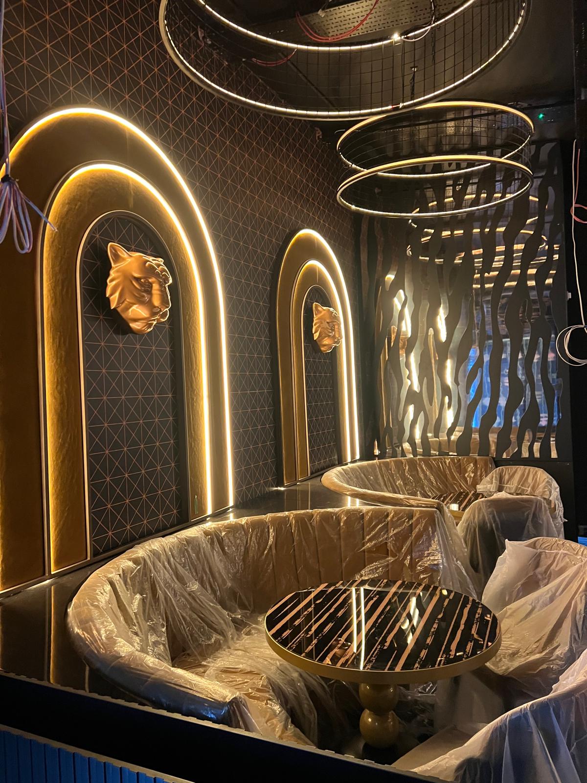 Completed booth seating beneath a gold arch feature and tiger wall motif, still in protective wrap