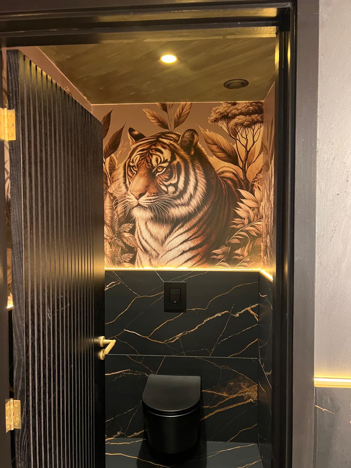 Completed WC cubicle with a large tiger mural and black sanitaryware