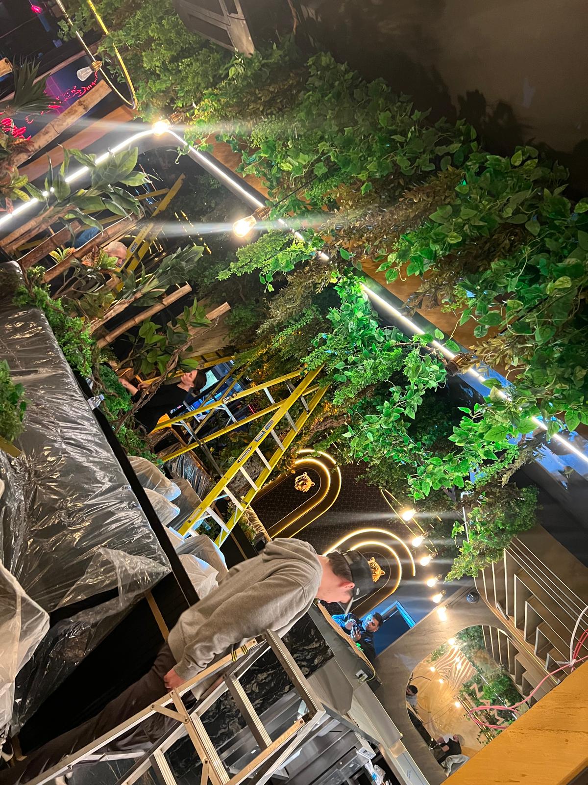 Artificial greenery canopy being installed across the ceiling